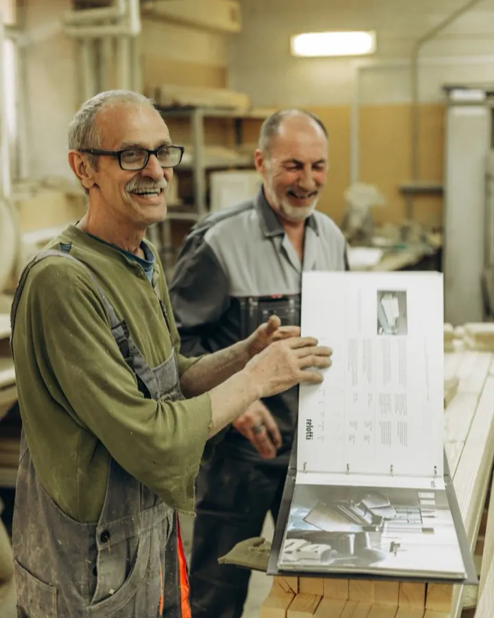 Deux artisans d'un atelier de menuiserie examinant des plans de travail ensemble.